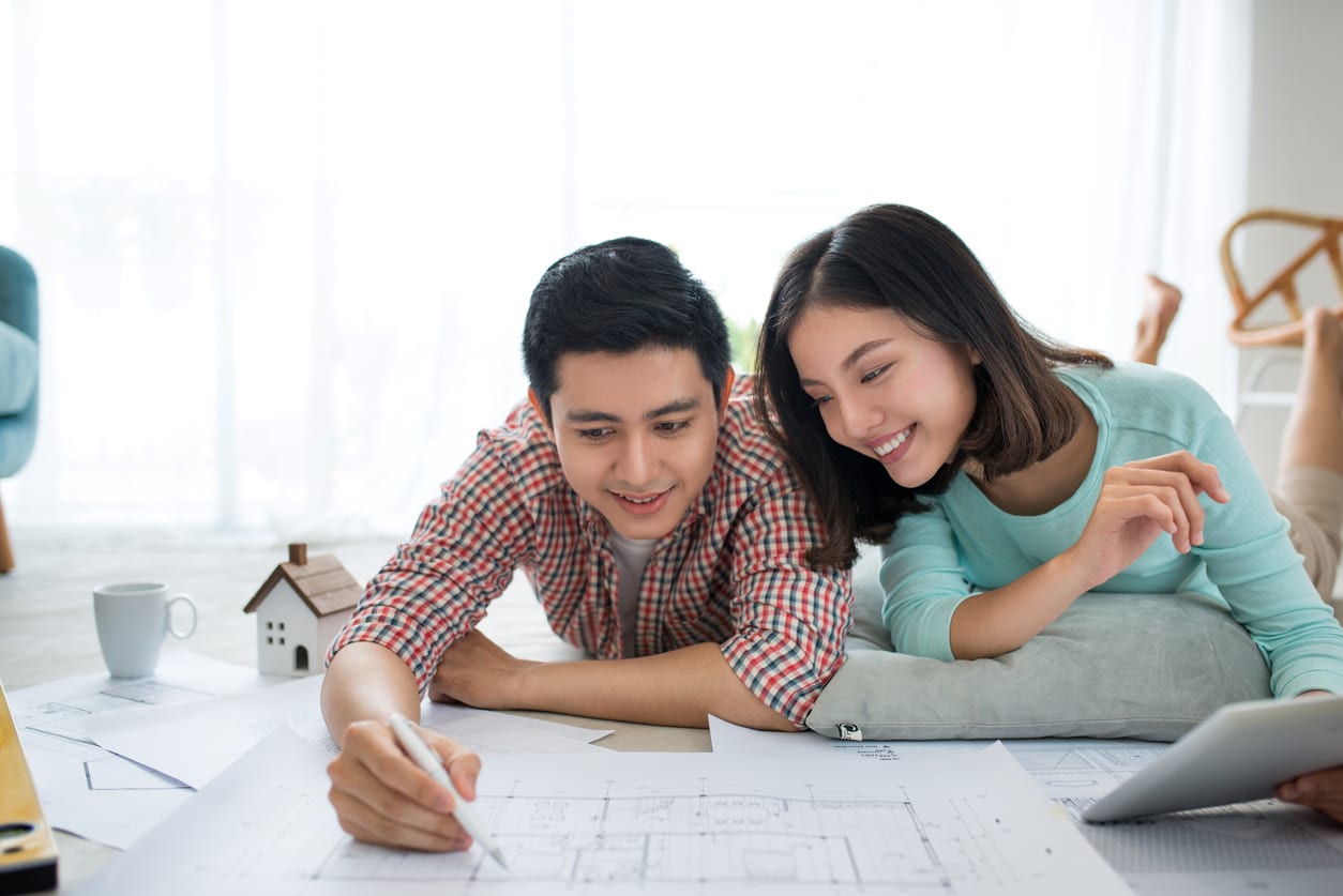 Attractive young asian adult couple looking at blue prints for an ADU in Hawaii.